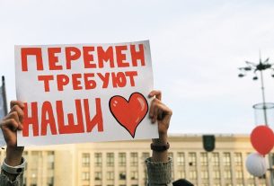 person holding red and white love is love print board