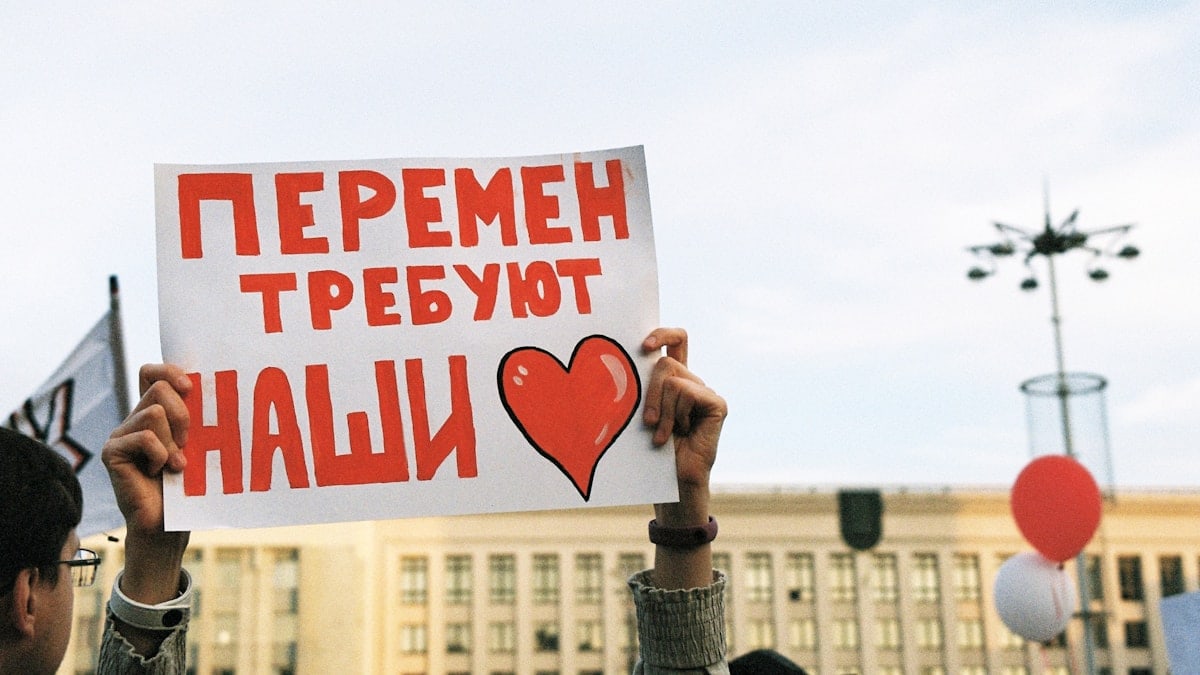 person holding red and white love is love print board
